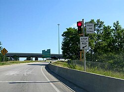 Image of a ramp meter: a small traffic light (red) installed on a highway on-ramp